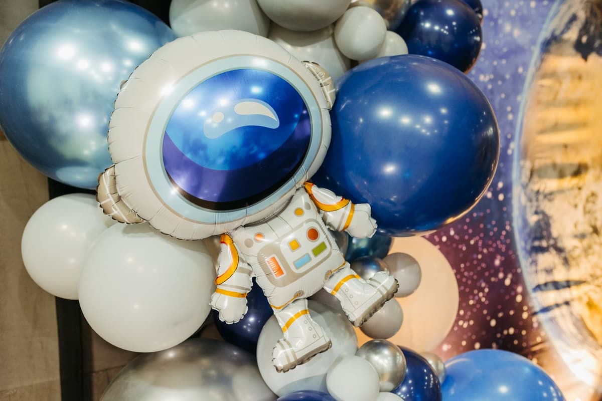 A whimsical astronaut balloon floats amid a vibrant array of blue and white balloons