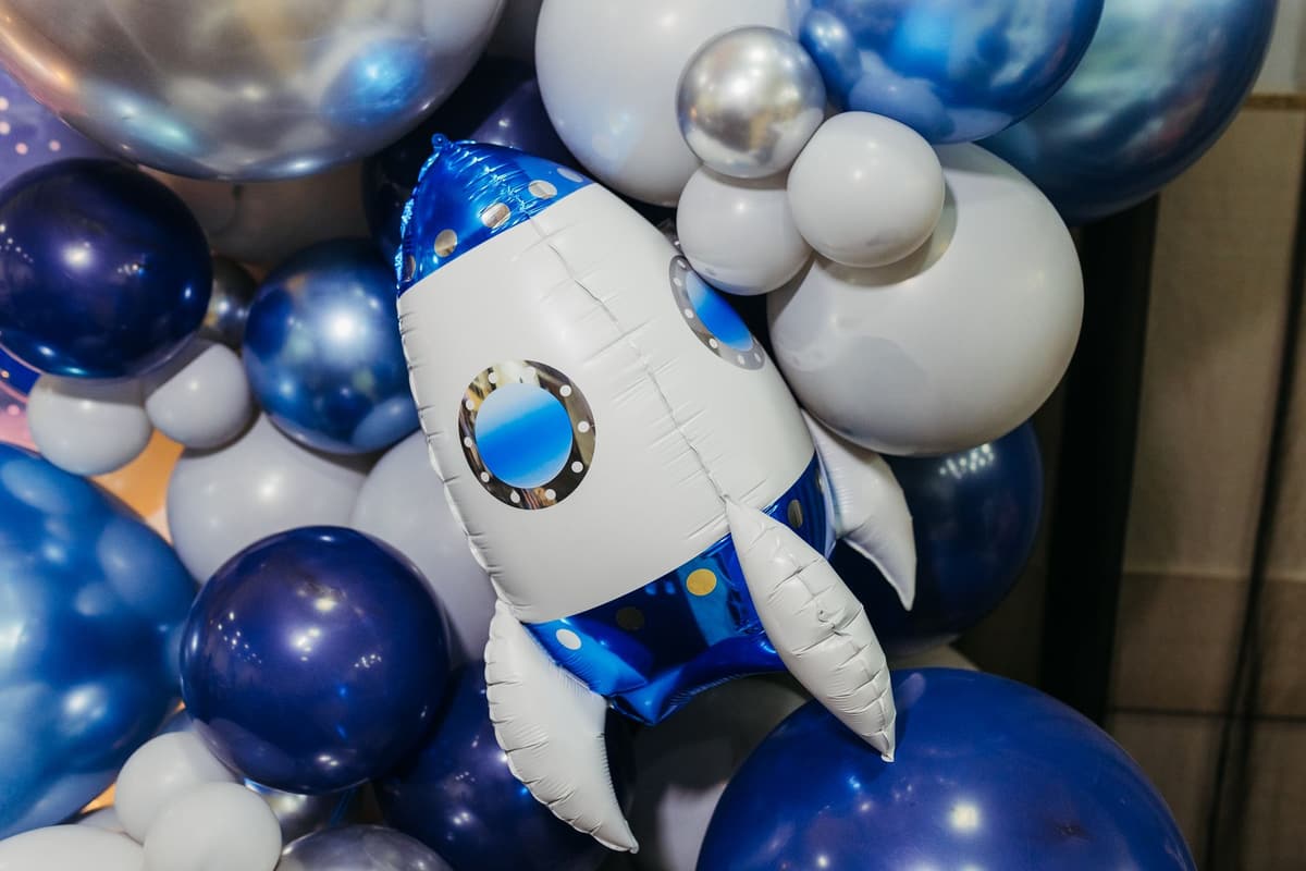 Colorful space-themed balloon arrangement with a rocket centerpiece. Perfect for parties