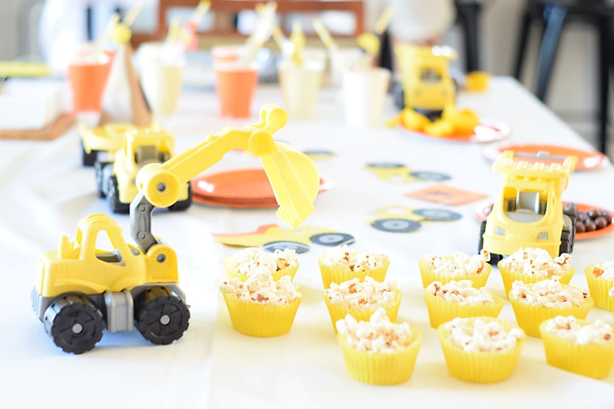 Bright construction-themed birthday party with yellow toy vehicles and cupcakes