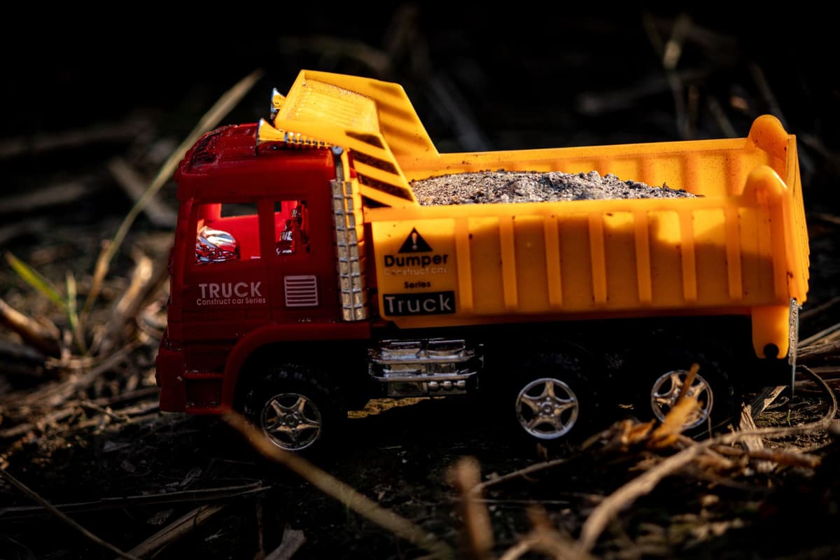 A vibrant toy dump truck filled with gravel, captured outdoors in natural lighting