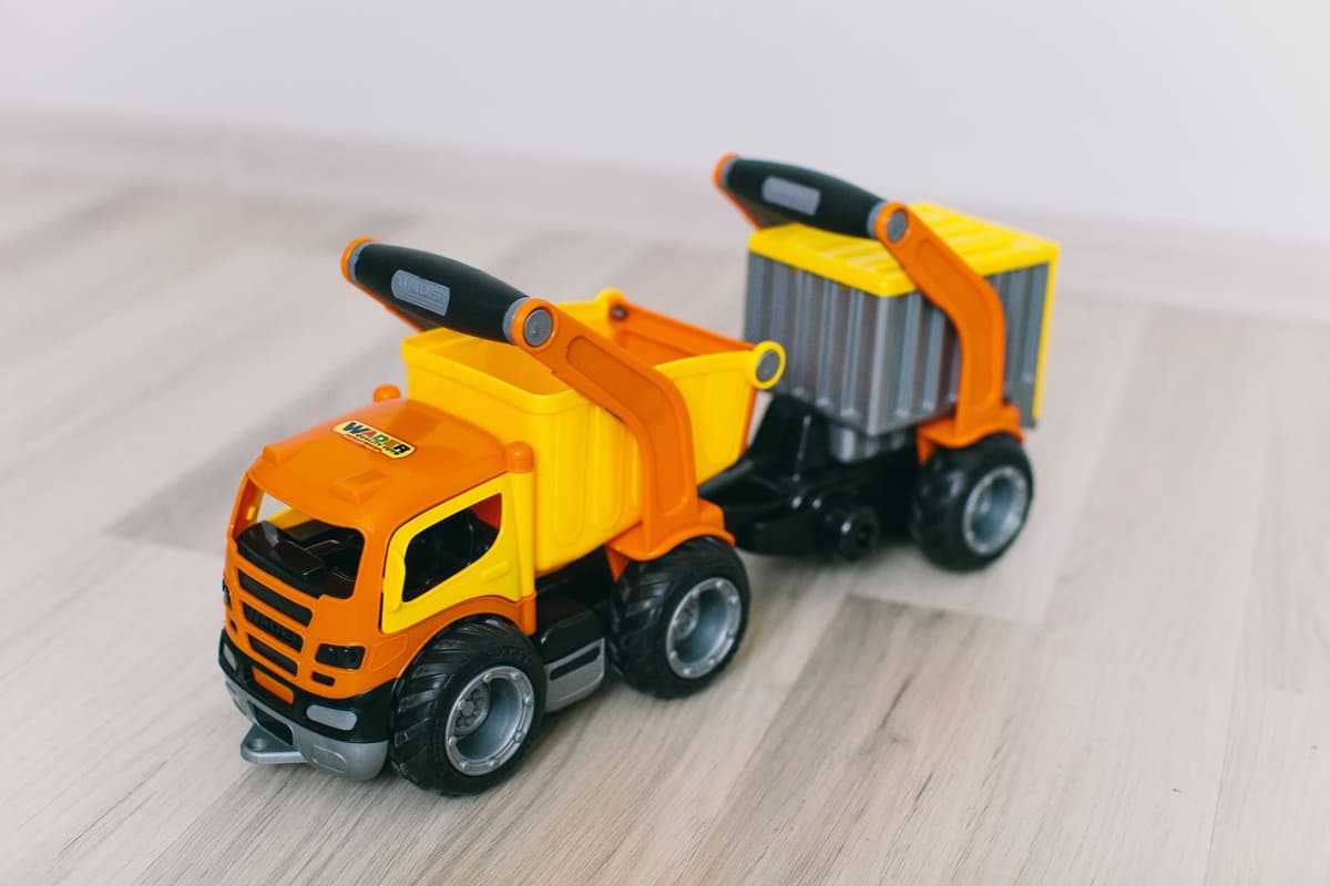Bright orange and yellow toy dump truck on light wooden floor, close-up view