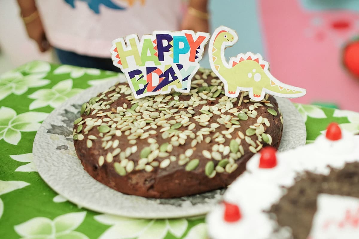 A fun dinosaur-themed birthday cake with colorful decorations and seeds