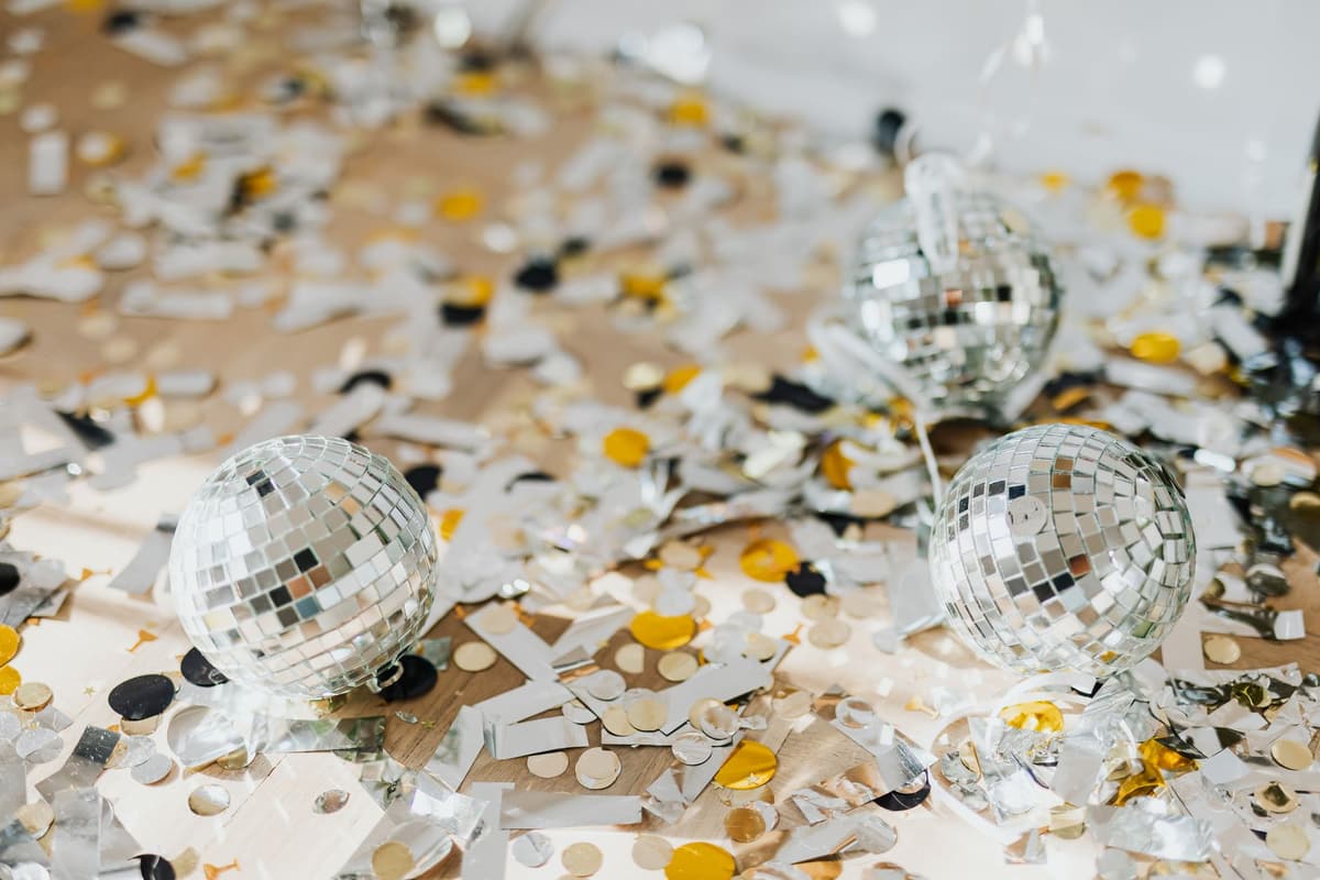 Close-up of disco balls surrounded by colorful confetti on a party table