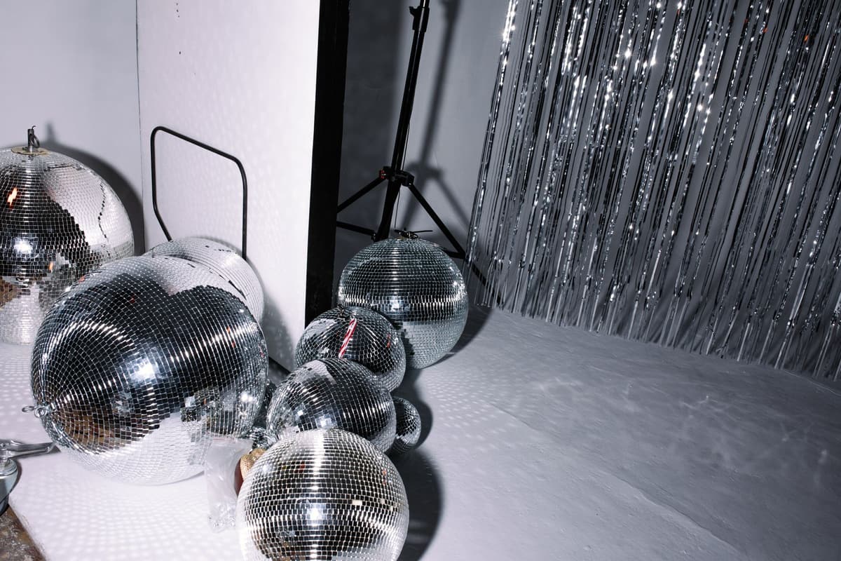 Cluster of disco balls and silver foil curtain in a studio setting creating a reflective atmosphere