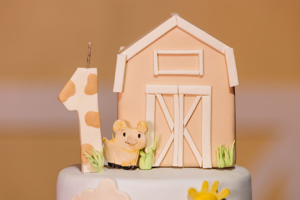 Cute first birthday cake topper with barn and piglet decoration in pastel colors