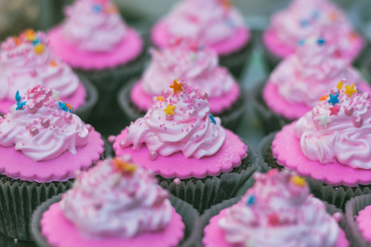Close-up of freshly baked pink cupcakes with colorful sprinkles and frosting