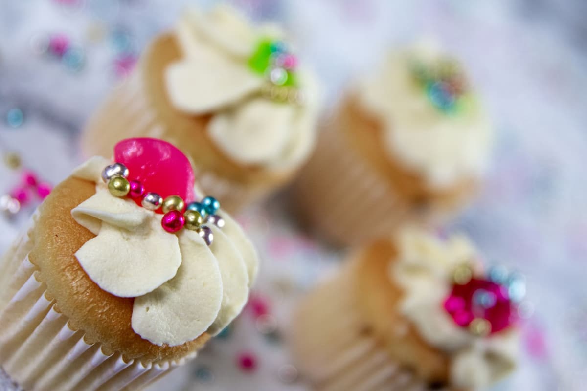 Close-up of decorated cupcakes featuring vibrant beads and creamy icing, perfect for dessert enthusiasts