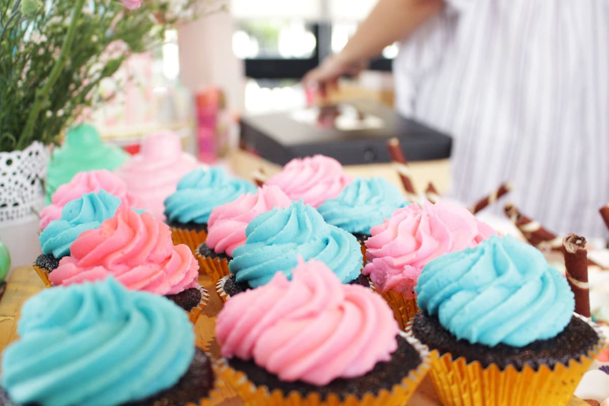 Vibrant pink and blue frosted cupcakes displayed on a table, ideal for dessert enthusiasts