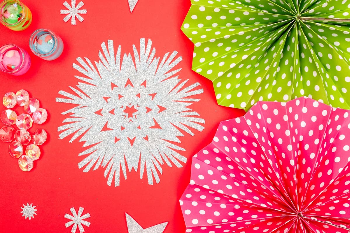 Colorful polka dot paper fans and glittering snowflake on red surface creating a festive atmosphere