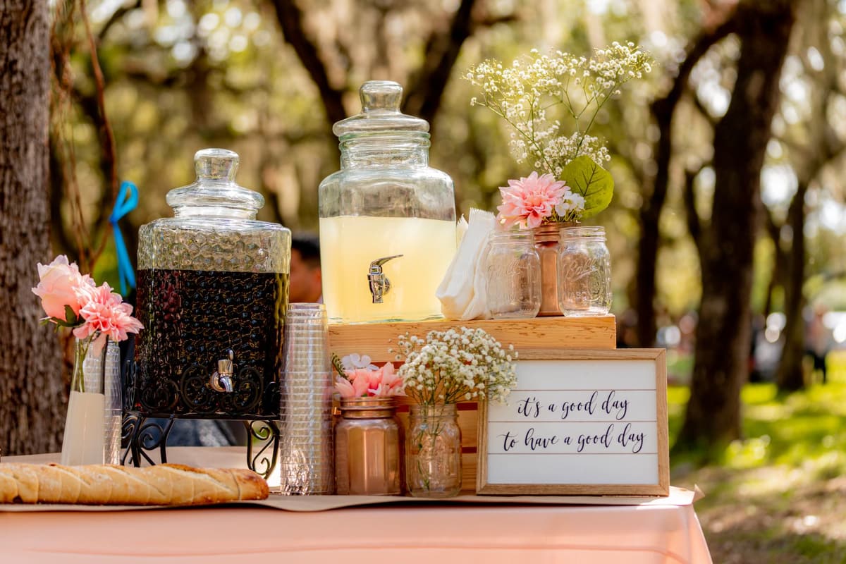 Rustic outdoor beverage table setup featuring lemonade and flowers for a celebration