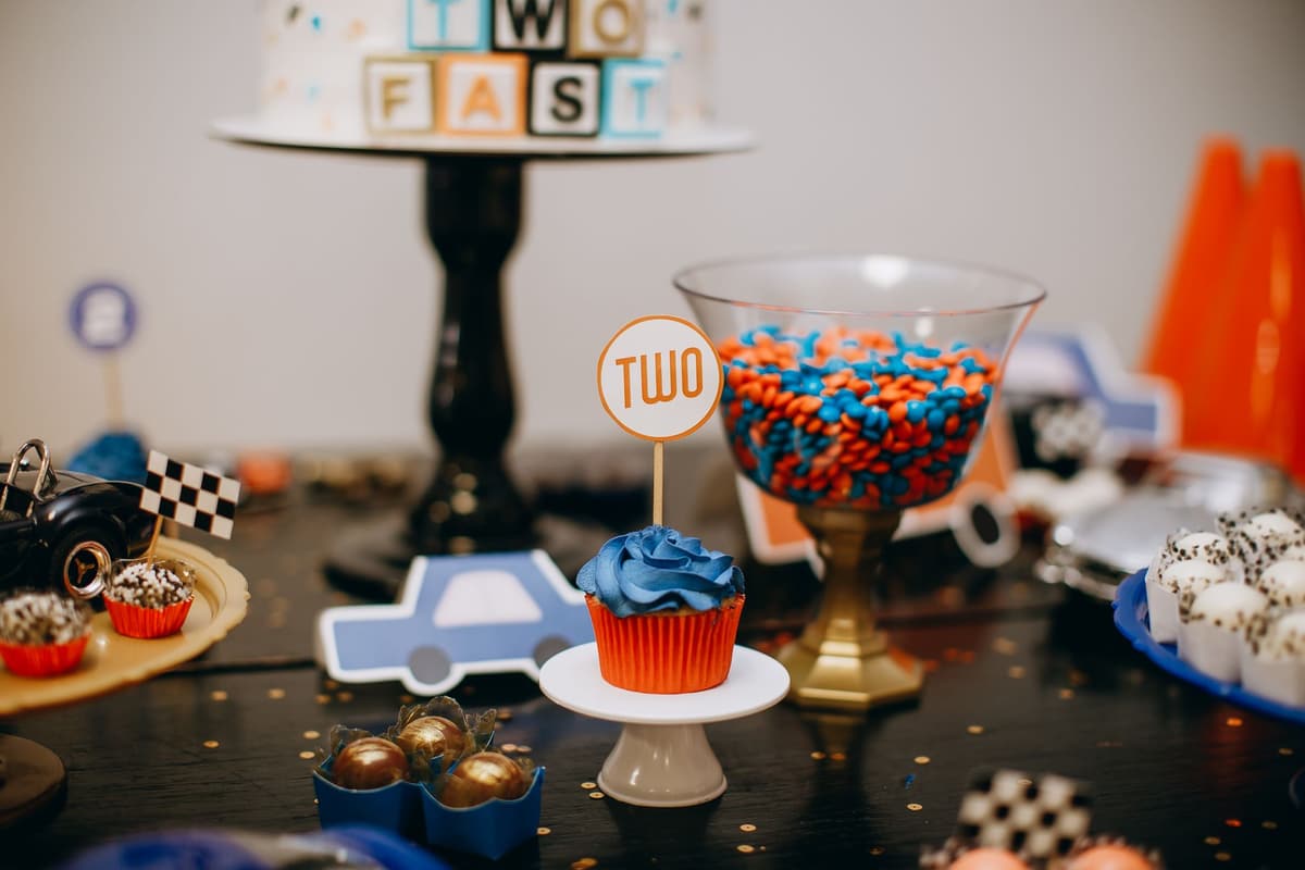 Vibrant car-themed birthday table with cupcakes, candy, and cake for two-year-old celebration