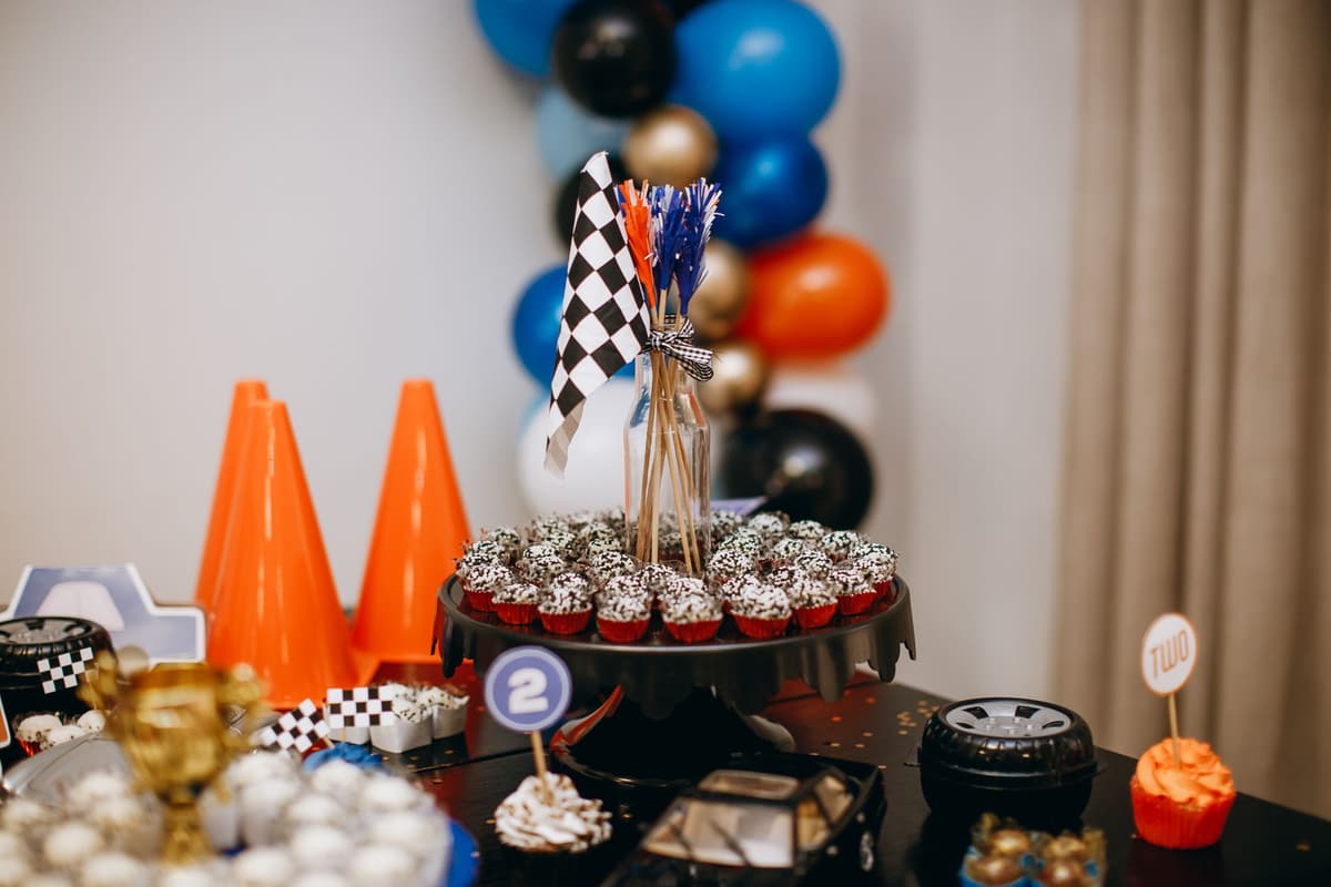 Racing themed party table with cupcakes, balloons, and checkered flags creating a festive atmosphere