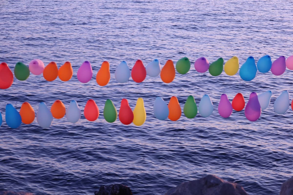 Vibrant balloons hanging above a calm sea creating a colorful visual contrast