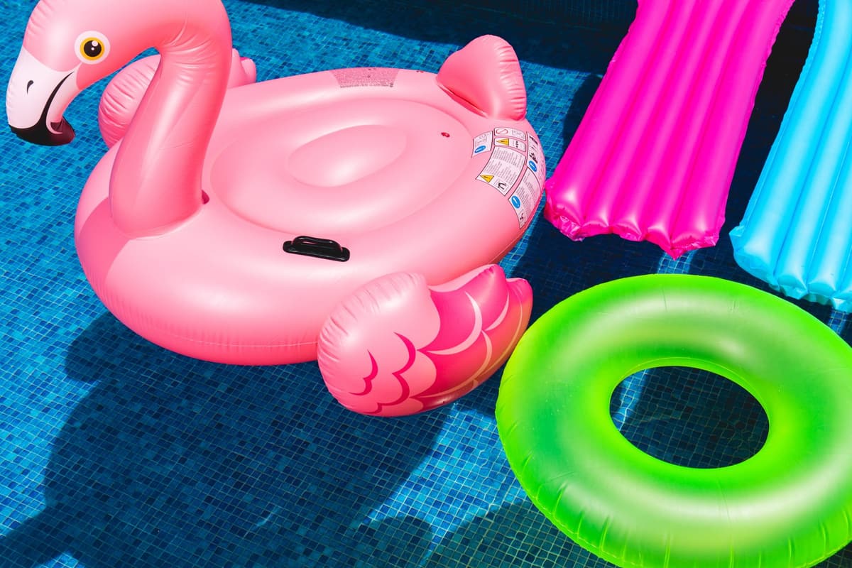Bright inflatable flamingo and rings floating in a sunny pool