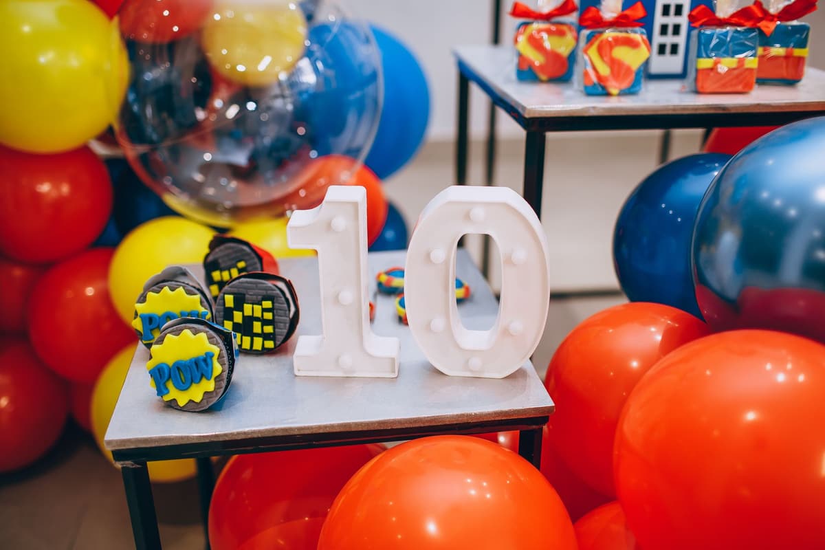 Vibrant celebration setup with balloons, number 10, and superhero-themed cupcakes