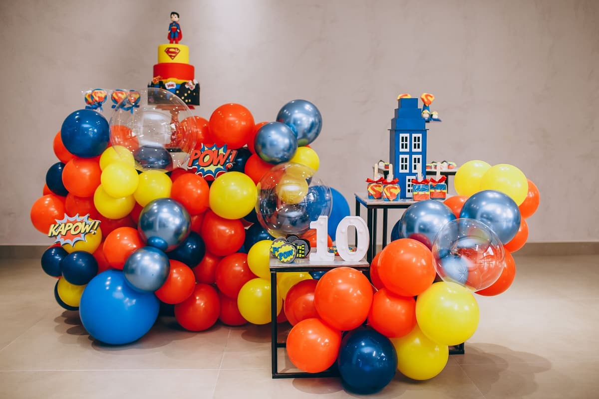 Colorful superhero themed birthday party decoration with balloons and cake