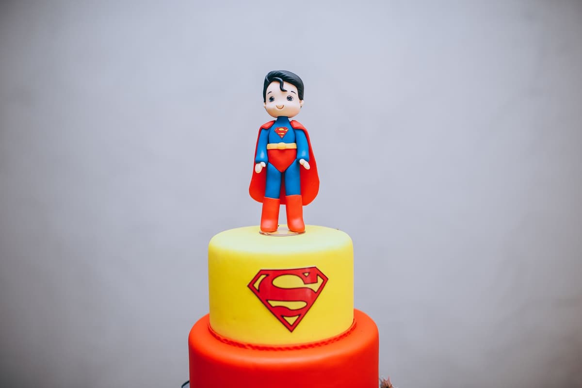 Colorful superhero cake featuring a fondant Superman figurine on top, perfect for themed parties