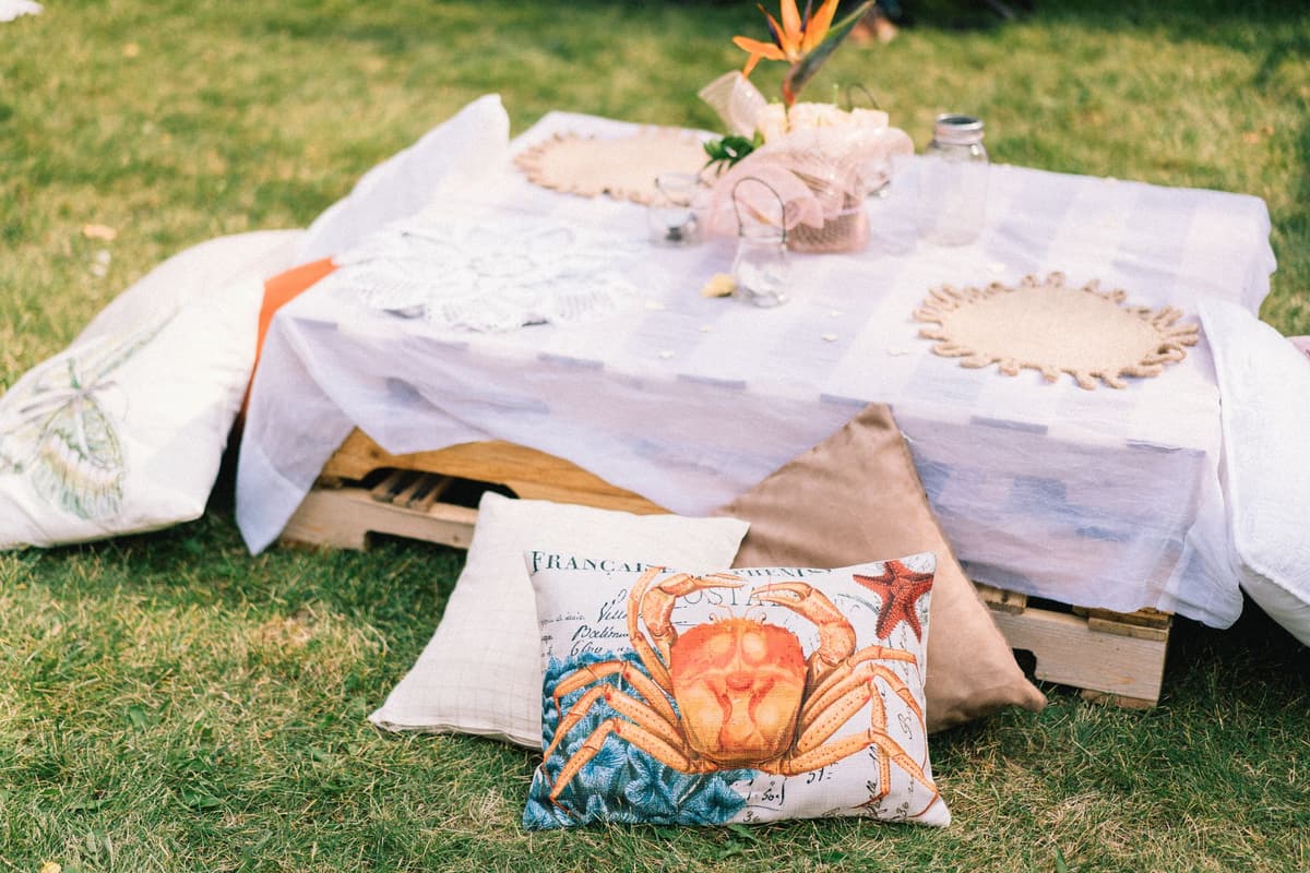 Cozy outdoor picnic arrangement featuring pillows and a pallet table on grass