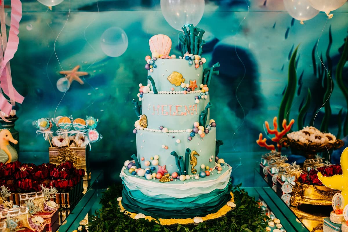 Assorted delicious sweets and desserts around tiered cake in theme of underwater flora and fauna